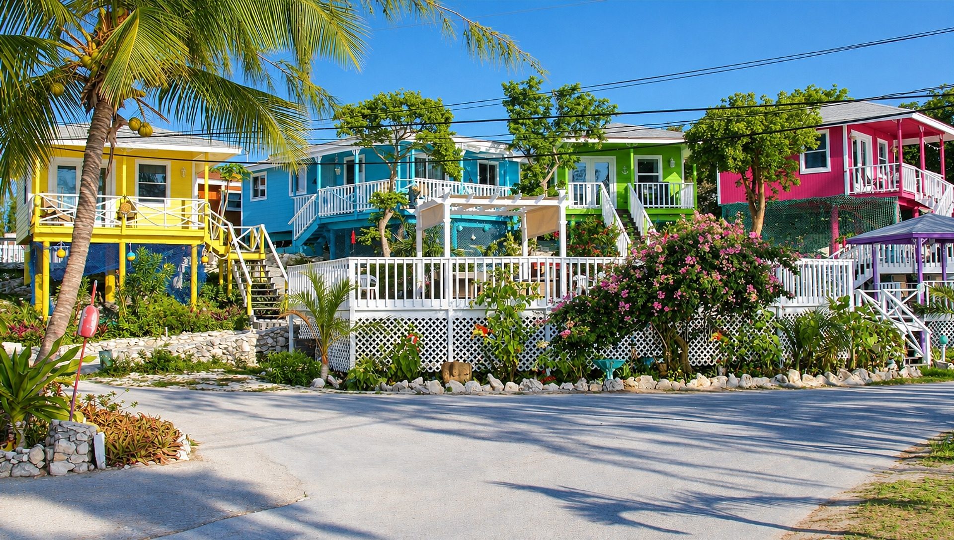 Row of colorful villas in yellow, teal, and pink along the garden lane